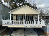 Charming raised beach house with covered porch and white railings, perfect for coastal living at 6001-O4 S Kings Hwy., Myrtle Beach, SC 29575