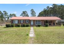 Charming brick home with a metal roof, a well-manicured lawn, and mature landscaping at 77 Towhee St., Georgetown, SC 29440