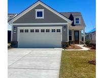 Charming gray home featuring a white two-car garage, well-manicured lawn, and classic architectural details at 1226 Crested Iris Way, North Myrtle Beach, SC 29582