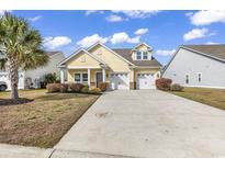 Charming yellow home featuring a well-manicured lawn and a two-car garage, with beautiful landscaping at 141 Southgate Ct., Pawleys Island, SC 29585