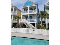 Charming three-story beach house featuring a vibrant blue exterior, white trim, and a welcoming staircase at 1411 N Waccamaw Dr., Murrells Inlet, SC 29576