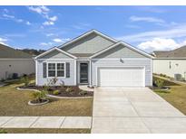 Charming single-story home with light blue siding, a well-manicured lawn, and an attached garage at 1616 Cosmos Lane, Myrtle Beach, SC 29577