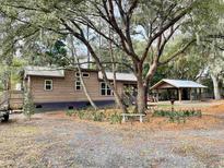 Charming home featuring wood siding, metal roof, and beautiful landscaping with a covered structure in the back at 3633 Kings River Rd., Pawleys Island, SC 29585