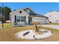 Charming single-story home with well-manicured landscaping, decorative accents, and a two-car garage at 134 Winding Path Dr., Loris, SC 29569