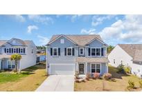 Charming two-story home with light blue siding, a two-car garage and a well-manicured front lawn on a sunny day at 3304 Candytuft Dr., Conway, SC 29526