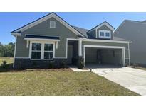 Charming single-Gathering home featuring green siding, stone accents, and an attached two-car garage at 3317 Sw Wood Stork Dr., Ocean Isle Beach, NC 28469
