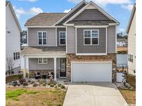 Charming two-story home featuring stone accents, a welcoming front porch, and an attached two-car garage at 511 Mcalister Dr., Little River, SC 29566
