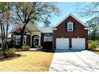 Charming brick home with a two-car garage, manicured lawn, and mature trees under a sunny sky at 728 Camden Circle, Pawleys Island, SC 29585