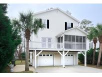 Inviting two-story home with a two-car garage and screened porch surrounded by lush tropical landscaping at 319 16Th Ave. S, Surfside Beach, SC 29575