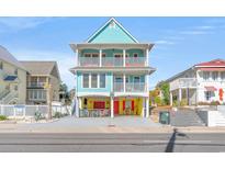 Charming three-story beach house with light blue accents, multiple balconies, and vibrant colors at 908 S Ocean Blvd., North Myrtle Beach, SC 29582