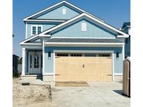 Charming two-story blue home featuring a light woodgrain garage door, classic architecture, and beautiful curb appeal at 921 Crystal Water Way, Myrtle Beach, SC 29579