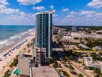 Oceanfront condo tower with coastal views, beach access, and nearby attractions under a partly cloudy, blue sky at 107 S Ocean Blvd. # 704, Myrtle Beach, SC 29577