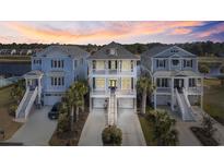 Beautiful waterfront home with dual elevated balconies, lush landscaping, and serene sunset backdrop at 296 West Palms Dr., Myrtle Beach, SC 29579