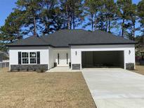 Charming home with black shutters, a grey roof, an open two-car garage and a well-manicured lawn at 311 St. Andrews Ln., Myrtle Beach, SC 29588