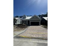 Charming home with a brick driveway, green siding, a white metal roof, and a lovely covered front porch at 382 Waties Dr., Murrells Inlet, SC 29576