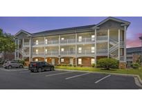 Three-story condo building showcasing walkways with white railings, green grass, and parking spaces at 3927 Gladiola Ct. # 101, Myrtle Beach, SC 29588