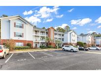 A condo exterior with a brick base, white siding, balconies, and parking spots at 4814 Innisbrook Ct. # 412, Myrtle Beach, SC 29579