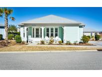Charming beach house with a covered porch, white Adirondack chairs, and a vibrant turquoise exterior at 5223 Sea Coral Way, North Myrtle Beach, SC 29582