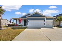 Charming home featuring a three car garage, manicured lawn, and inviting front porch adorned with flags at 900 Pelagic Loop, Myrtle Beach, SC 29579