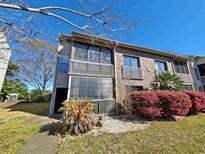Exterior view of a condo with brick and siding, a screened porch, and decorative landscaping at 1356 Glenns Bay Rd. # 201B, Surfside Beach, SC 29575