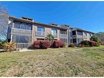 Brick condo with two levels of screened-in patios and manicured shrubbery against a blue sky at 1356 Glenns Bay Rd. # 201B, Surfside Beach, SC 29575