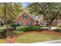 Beautiful brick home with lush landscaping, mature trees, and classic architectural details at 192 Berkshire Loop, Pawleys Island, SC 29585