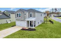 Charming two-story home featuring a manicured lawn, attached garage, and covered front porch for welcoming guests at 204 Leaflet Loop, Pawleys Island, SC 29585