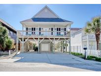 Two-story beach house on stilts with a double porch and ground-level garage and a large paved driveway at 209 30Th Ave. N, North Myrtle Beach, SC 29582