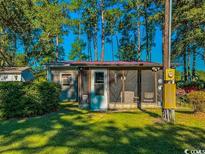 Charming home with screened porch, surrounded by lush greenery and mature trees at 3641 Half Pint Rd., Longs, SC 29568