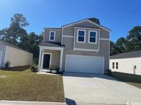 Charming two-story home with attached two car garage and manicured lawn on a sunny day at 407 Ladyfish Loop, Sunset Beach, NC 28468