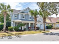 Charming two-story home featuring gray siding, inviting front porch, and well-manicured landscaping with palm trees at 452 Banyan Place, North Myrtle Beach, SC 29582