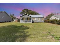 Charming gray cottage with a metal roof and a welcoming front porch and spacious grassy yard at 606 Britt St., Georgetown, SC 29440