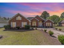 Charming brick home with manicured lawn and inviting curb appeal under a colorful sunset sky at 650 Buck Trail, Longs, SC 29568