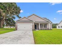 Charming single-Gathering home with a two-car garage, lush lawn, and classic design under a clear blue sky at 72 Millsite Ct., Georgetown, SC 29440