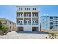 Stunning three-story beach house featuring multi-level balconies, covered parking, and attractive landscaping at 937 Ocean Blvd. S, North Myrtle Beach, SC 29582