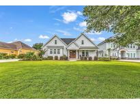 Charming white farmhouse-style home with a well-manicured lawn and inviting front porch at 1121 Glossy Ibis Dr., Conway, SC 29526