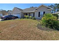 Charming single-story home with well-manicured landscaping and a gray car parked in the driveway at 221 Black Bear Rd., Myrtle Beach, SC 29588