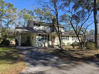 Charming two-story home featuring a carport, manicured lawn, and mature trees providing shade at 2240 Jackson Circle, Little River, SC 29566