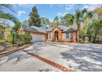 Charming brick home featuring a spacious driveway, blue shutters, and well-manicured landscaping at 74 Dornoch Dr., Pawleys Island, SC 29585