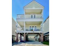 Three-story beach house with a light yellow exterior, white railings, and brick foundation at 113B 15Th Ave. S, Surfside Beach, SC 29575