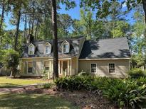 Charming home with dormer windows, chimney, green shutters, and mature landscaping at 133 Otter Run Rd., Pawleys Island, SC 29585