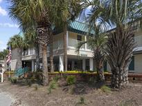 Inviting condo exterior surrounded by lush palm trees and well-maintained landscaping at 1 Norris Dr. # 249, Pawleys Island, SC 29585