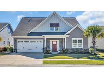 Charming home showcasing well-manicured landscaping, a two-car garage, and inviting front porch seating at 1109 Bonnet Dr., North Myrtle Beach, SC 29582