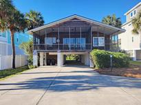Charming stilt house with screened porch, palm trees, and covered parking underneath at 312 Norris Dr., Pawleys Island, SC 29585