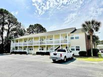 Exterior view of a two-story condominium building with white balconies and ample parking at 4150 Horseshoe Rd. N # 8, Little River, SC 29566