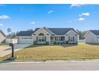 Charming single-story home with a well-manicured front yard and attached two-car garage on a sunny day at 480 Oakham Dr., Conway, SC 29527