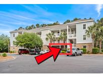 Exterior view of a multi-story condo building with palm trees and a parking area at 6253 Catalina Dr. # 713, North Myrtle Beach, SC 29582