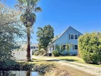 Charming two-story home with a blue exterior, mature landscaping, and a serene pond view at 613 23Rd Ave. N, North Myrtle Beach, SC 29582