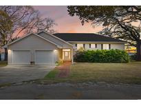 Charming single-story home featuring an attached two car garage, inviting front porch, and a manicured lawn at 110 Hickory St., Sunset Beach, NC 28468