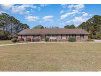 A charming single-story brick home with a well-manicured lawn and inviting curb appeal in a sunny day at 313 Blue Ridge Dr., Pawleys Island, SC 29585